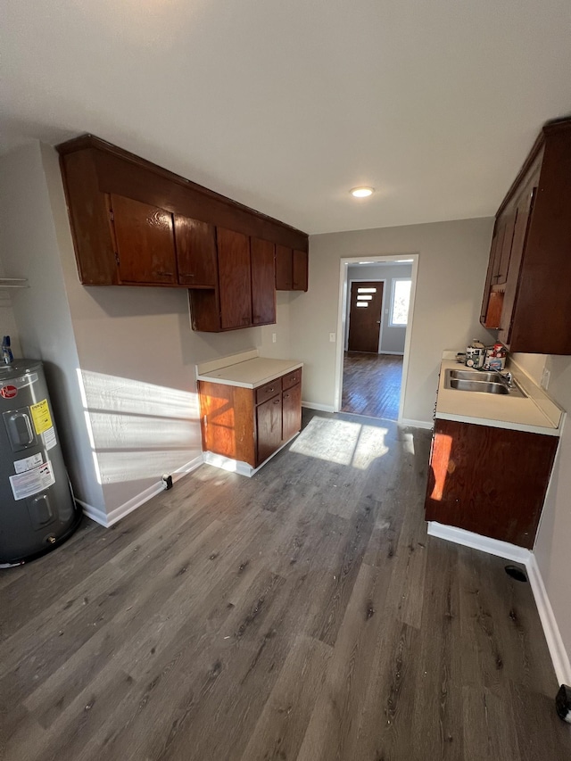 kitchen with dark brown cabinetry, light countertops, dark wood-style flooring, and electric water heater