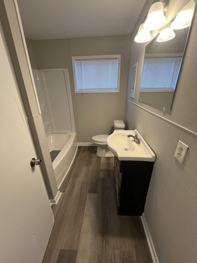 full bathroom with tile walls, toilet, vanity, wood finished floors, and baseboards