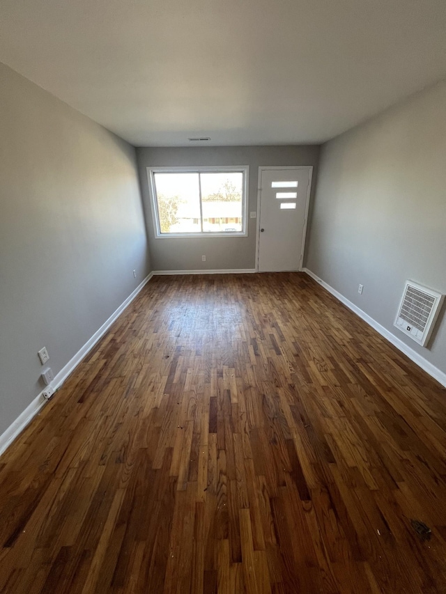 unfurnished living room with dark wood-style floors, visible vents, and baseboards