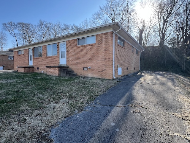 view of front of property featuring aphalt driveway, brick siding, entry steps, crawl space, and a front lawn