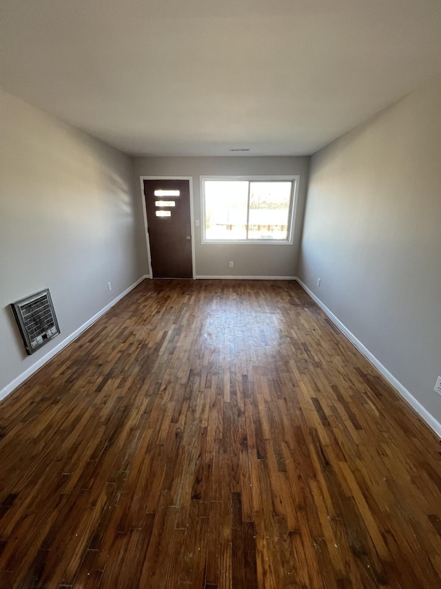 interior space with dark wood-style floors, baseboards, and heating unit