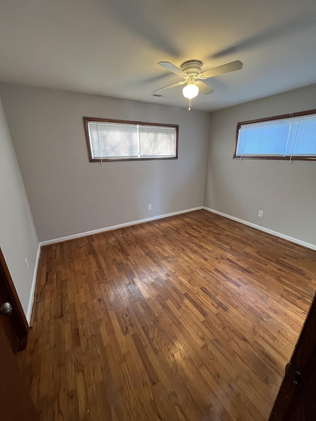 unfurnished room with dark wood-style flooring, ceiling fan, and baseboards