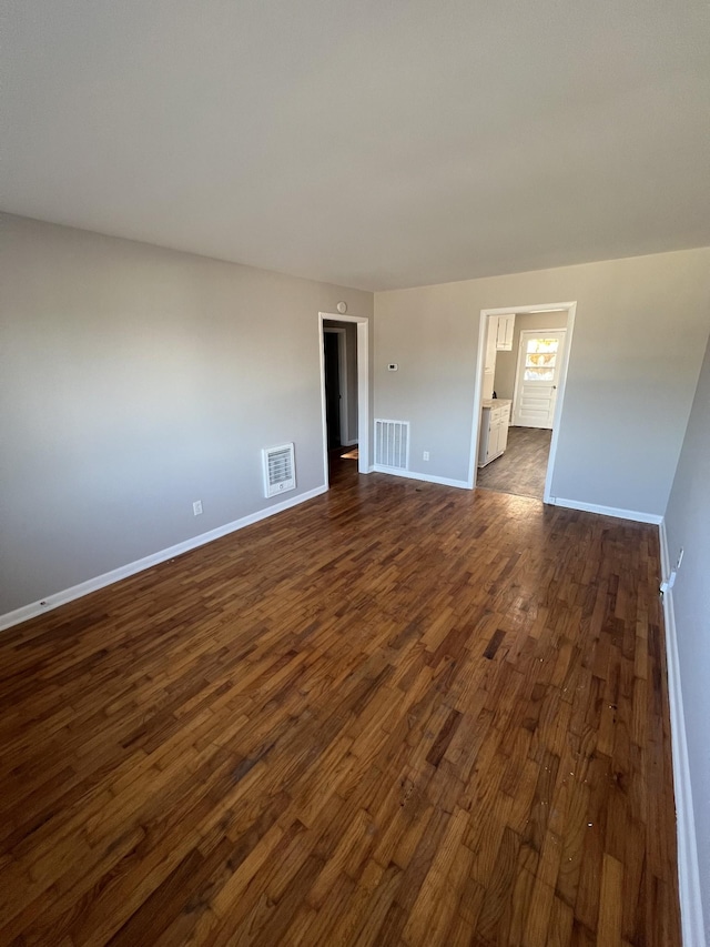 spare room with baseboards, visible vents, and dark wood-style flooring