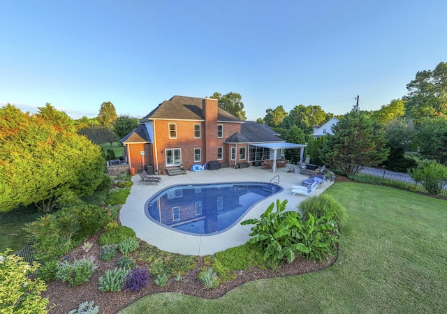 outdoor pool with a yard, a patio area, and fence