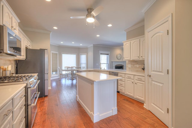 kitchen featuring stainless steel appliances, light countertops, light wood-style floors, white cabinetry, and a kitchen island