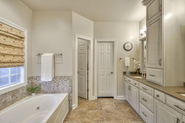 bathroom featuring baseboards, a sink, a whirlpool tub, and double vanity