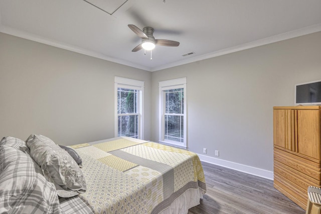 bedroom featuring ceiling fan, wood finished floors, visible vents, baseboards, and crown molding