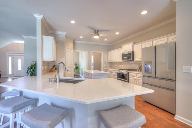 kitchen featuring appliances with stainless steel finishes, a breakfast bar, a sink, and a peninsula