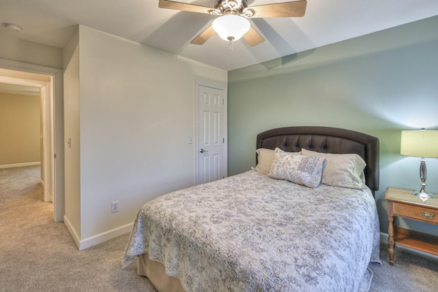 bedroom featuring light carpet, a ceiling fan, and baseboards