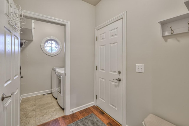 washroom featuring laundry area, wood finished floors, washing machine and dryer, and baseboards