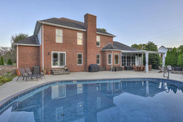 pool with entry steps, a patio area, and grilling area