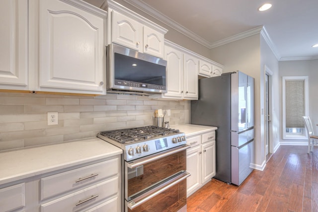 kitchen with white cabinets, decorative backsplash, appliances with stainless steel finishes, ornamental molding, and light countertops