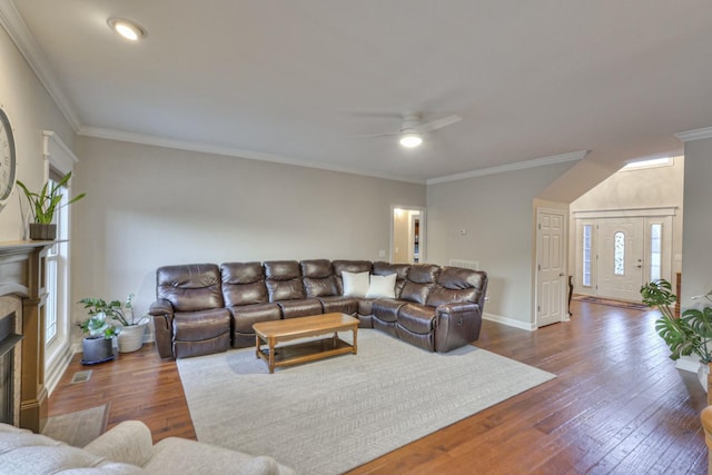 living room featuring baseboards, dark wood finished floors, a ceiling fan, ornamental molding, and a fireplace