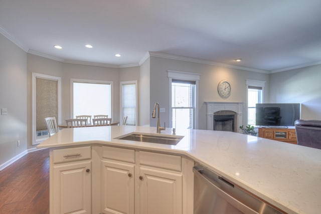 kitchen with dark wood finished floors, dishwasher, ornamental molding, open floor plan, and a sink