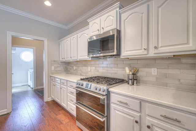 kitchen featuring white cabinetry, appliances with stainless steel finishes, backsplash, dark wood finished floors, and crown molding