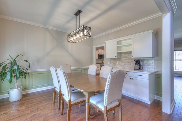 dining room with ornamental molding, wainscoting, a decorative wall, and dark wood-style floors