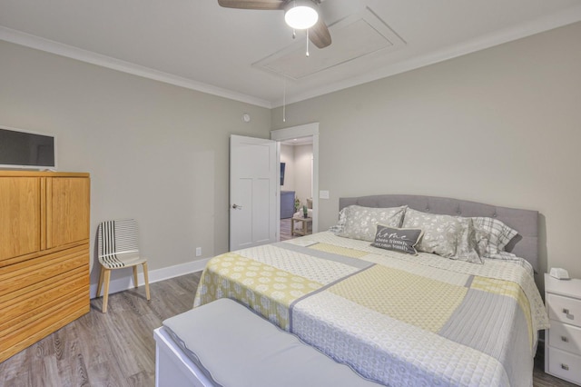 bedroom featuring crown molding, attic access, a ceiling fan, wood finished floors, and baseboards