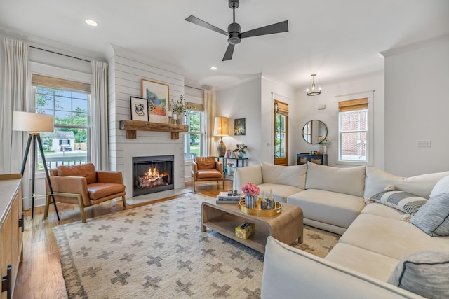 living area with light wood-type flooring, a healthy amount of sunlight, a fireplace, and recessed lighting