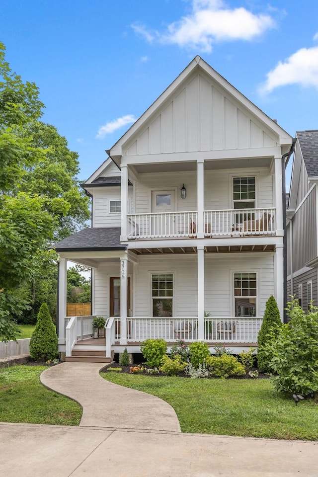 view of front of house with a balcony, covered porch, board and batten siding, and a front yard