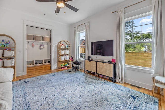 interior space featuring a ceiling fan, visible vents, baseboards, and wood finished floors