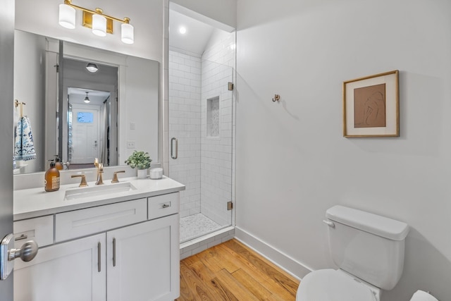 full bathroom with toilet, a stall shower, vanity, wood finished floors, and baseboards