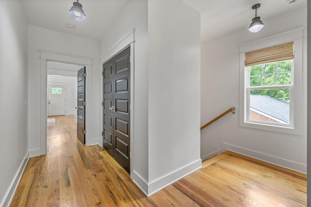 hallway featuring an upstairs landing, baseboards, and wood finished floors