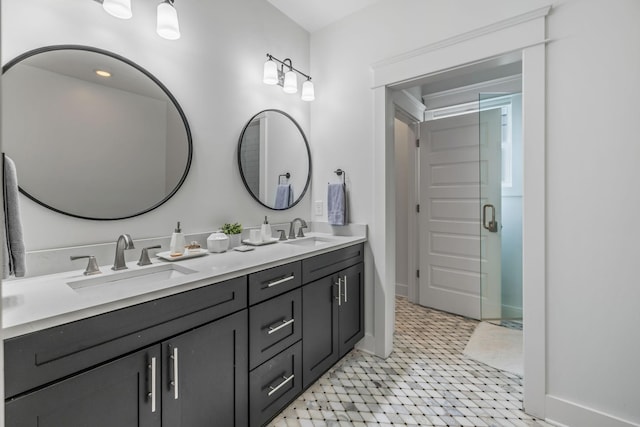 bathroom featuring a stall shower, a sink, baseboards, and double vanity