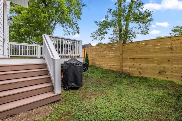 view of yard with a fenced backyard, a deck, and stairs