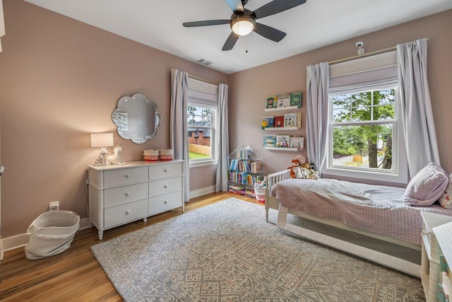 bedroom featuring light wood finished floors, a ceiling fan, visible vents, and baseboards