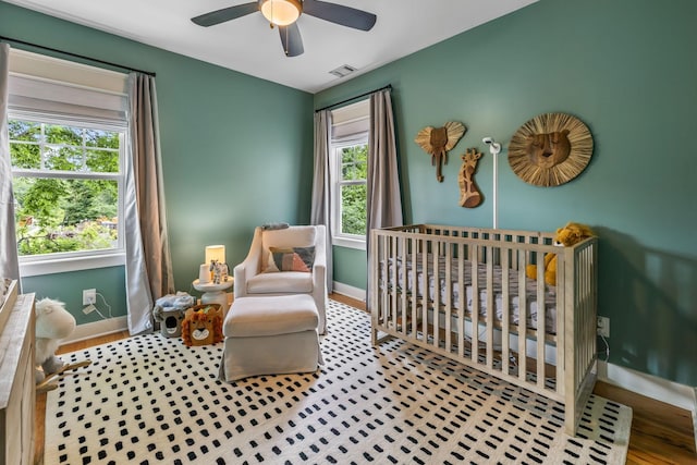 bedroom with a nursery area, baseboards, multiple windows, and visible vents