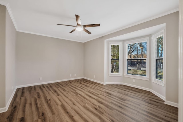 empty room with crown molding, baseboards, and wood finished floors