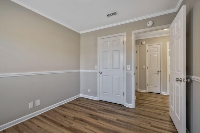 unfurnished bedroom featuring ornamental molding, visible vents, dark wood finished floors, and baseboards