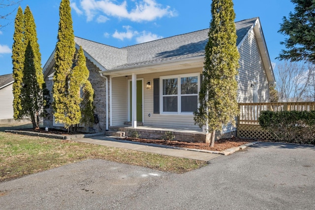 view of front of house featuring a shingled roof, a porch, and brick siding