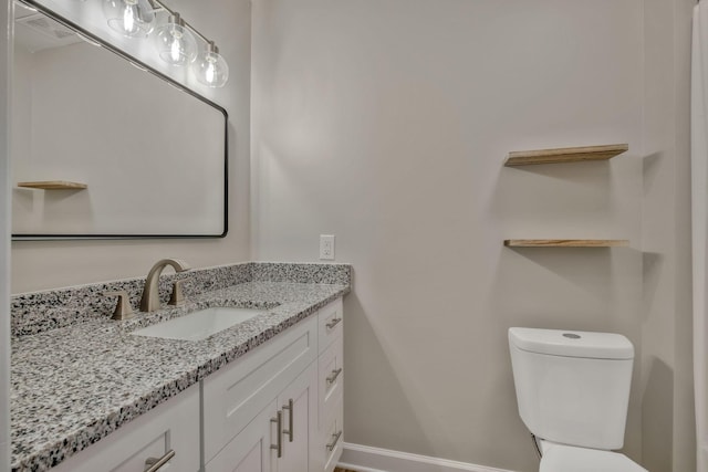 half bath featuring vanity, toilet, and baseboards