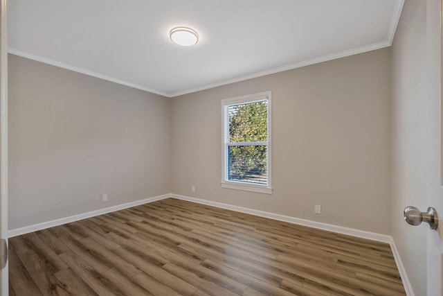 empty room with ornamental molding, wood finished floors, and baseboards