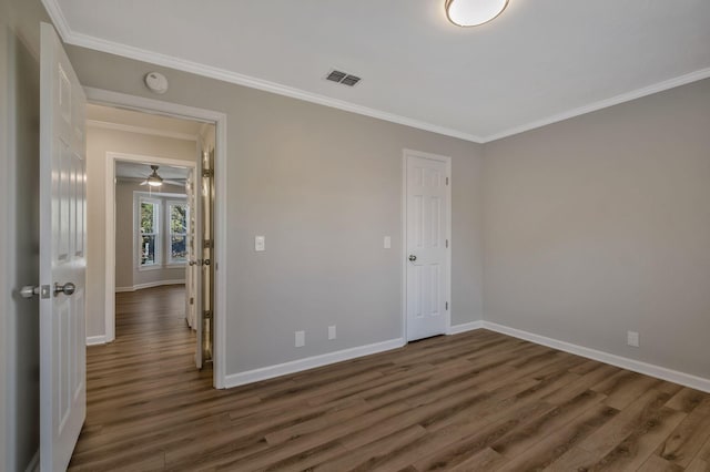 unfurnished room with dark wood-style floors, visible vents, ornamental molding, and baseboards