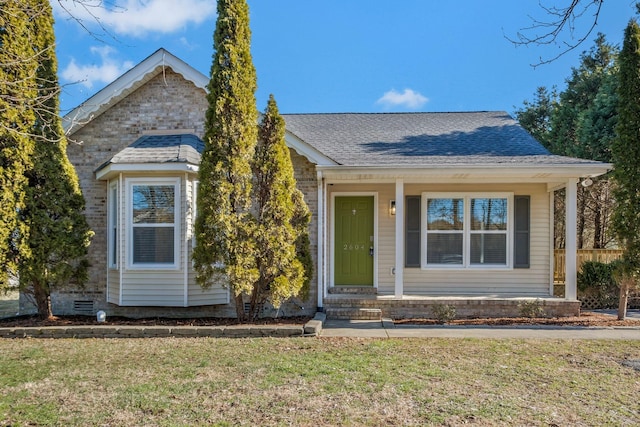 view of front of house featuring crawl space, a shingled roof, a front lawn, and brick siding