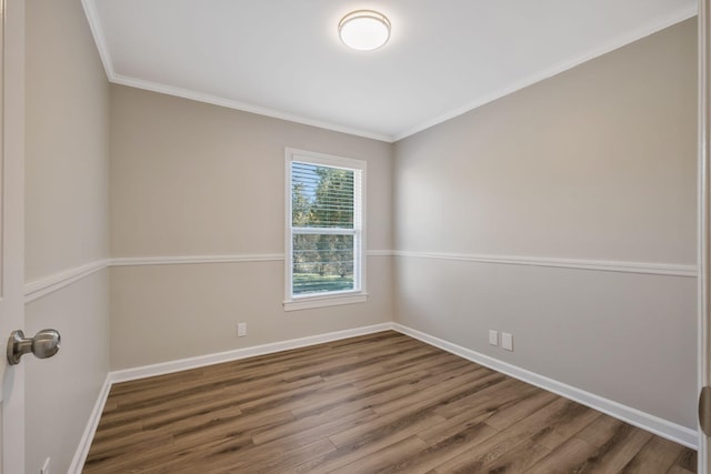 empty room featuring ornamental molding, wood finished floors, and baseboards