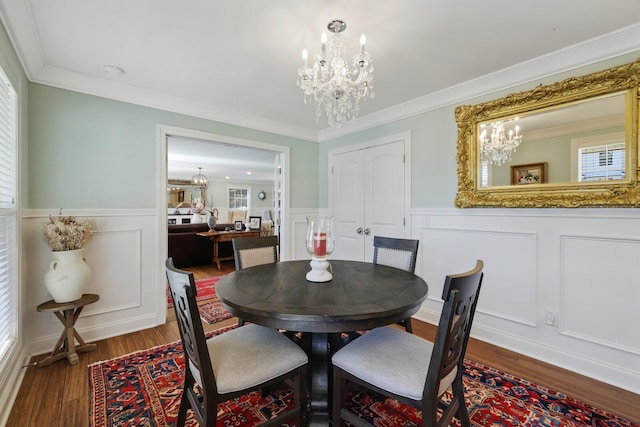 dining area with wainscoting, ornamental molding, a notable chandelier, and wood finished floors