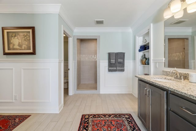 bathroom featuring ornamental molding, visible vents, toilet, and tiled shower