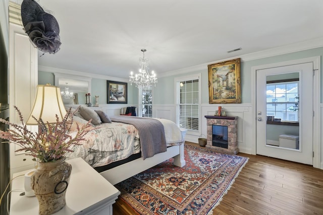 bedroom featuring an inviting chandelier, wood finished floors, visible vents, and crown molding