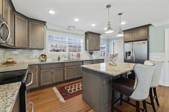 kitchen with crown molding, stainless steel appliances, a sink, and wood finished floors