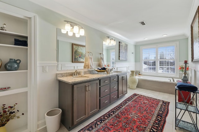 bathroom featuring double vanity, visible vents, a wainscoted wall, ornamental molding, and a sink