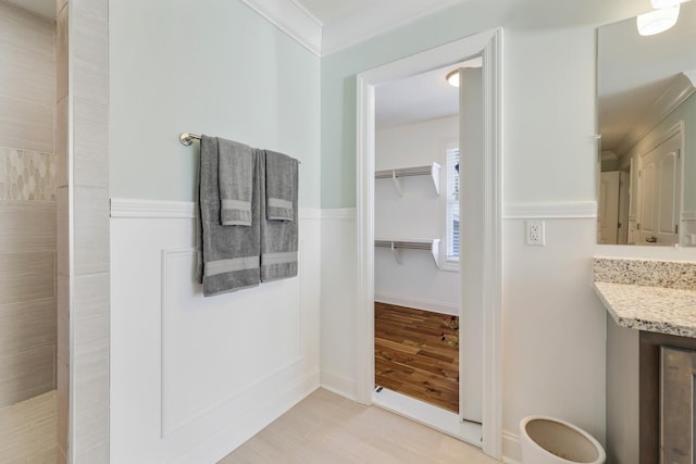 full bath with crown molding, a tile shower, baseboards, and wood finished floors