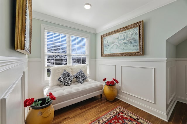 living area with ornamental molding, wainscoting, a decorative wall, and wood finished floors