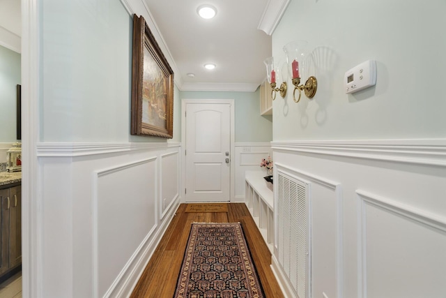 hall with a wainscoted wall, crown molding, recessed lighting, a decorative wall, and wood finished floors