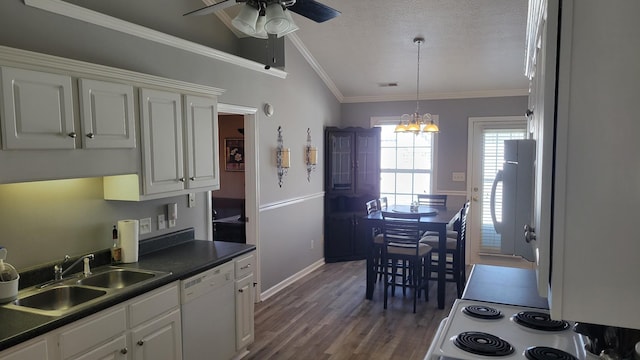 kitchen featuring dark countertops, white dishwasher, a sink, and white cabinetry