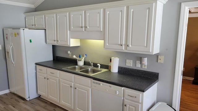 kitchen featuring dark countertops, white appliances, white cabinets, and a sink