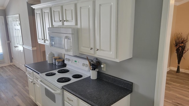 kitchen featuring dark countertops, white appliances, white cabinetry, and light wood-style flooring