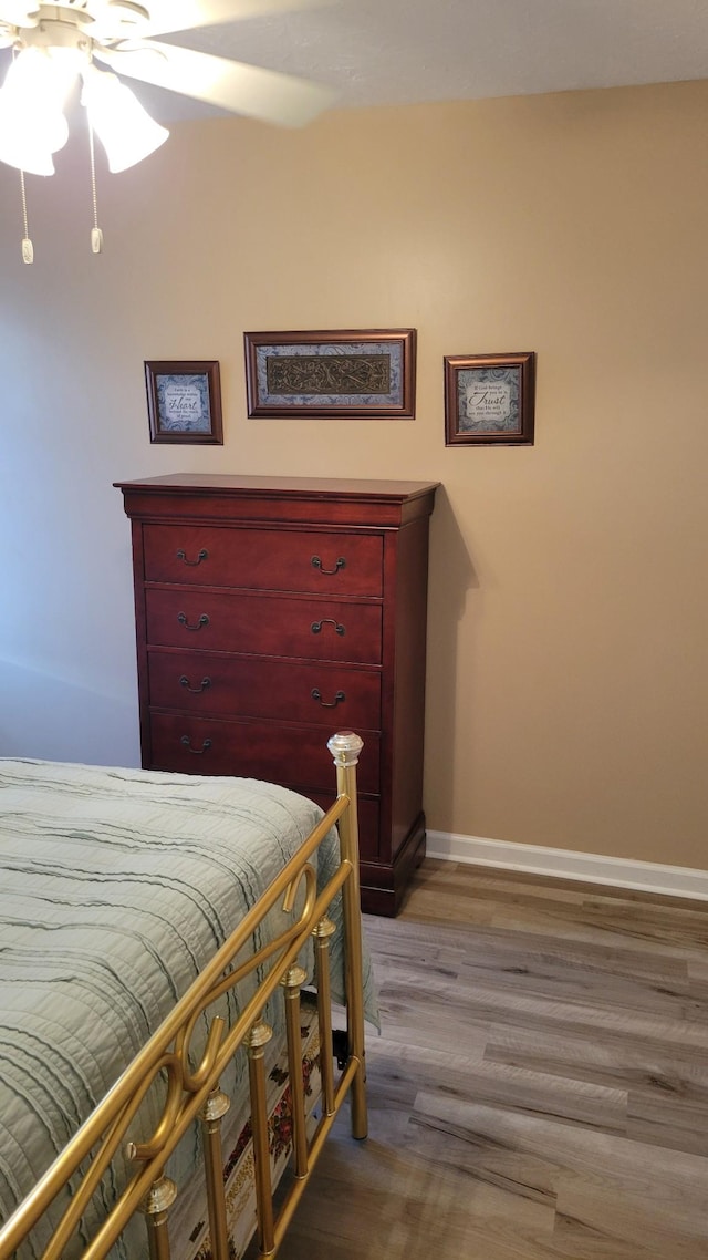 bedroom featuring ceiling fan, baseboards, and wood finished floors